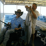 Adaptive fishing quadriplegic man in power wheelchair on boat with huge fish